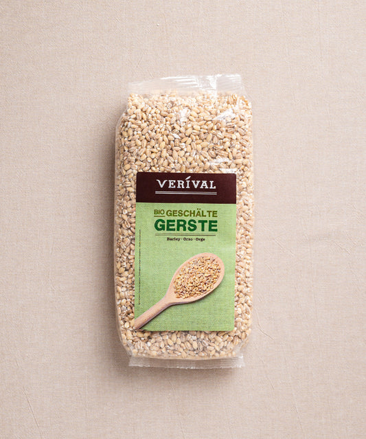Eine Packung ballaststoffreiche Bio-Gerste der Verival Bio GmbH liegt auf einem beigen Untergrund. Das Etikett zeigt einen Holzlöffel mit Perlgraupenkörnern und betont damit die natürliche cholesterinsenkende Wirkung.