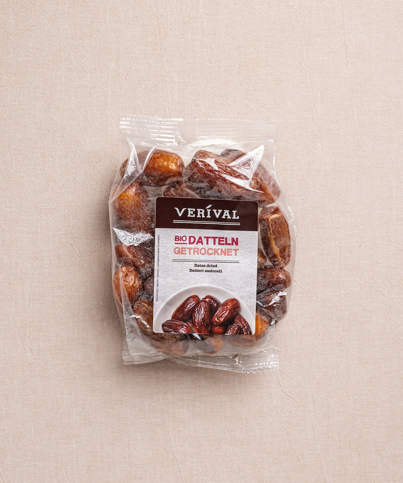 Auf einem beigen Untergrund liegt eine Packung getrockneter Datteln von Verival Bio, die auf Deutsch und Englisch beschriftet ist und den Verzicht auf Konservierungsstoffe unterstreicht.
