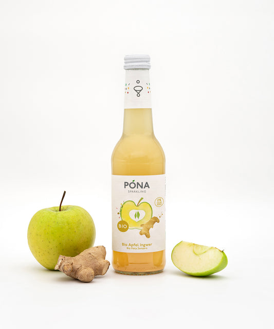 Eine Flasche PONA Apfel-Ingwer steht zentriert vor einem schlichten Hintergrund, umgeben von einem ganzen grünen Apfel, einer Ingwerwurzel und einer Apfelscheibe. Die Apfel-Ingwer-Mischung besteht aus Bio-Fruchtsaft und reinem Gebirgsquellwasser. Für den erfrischenden Geschmack sorgt die Wonderful Biodrinks GmbH.