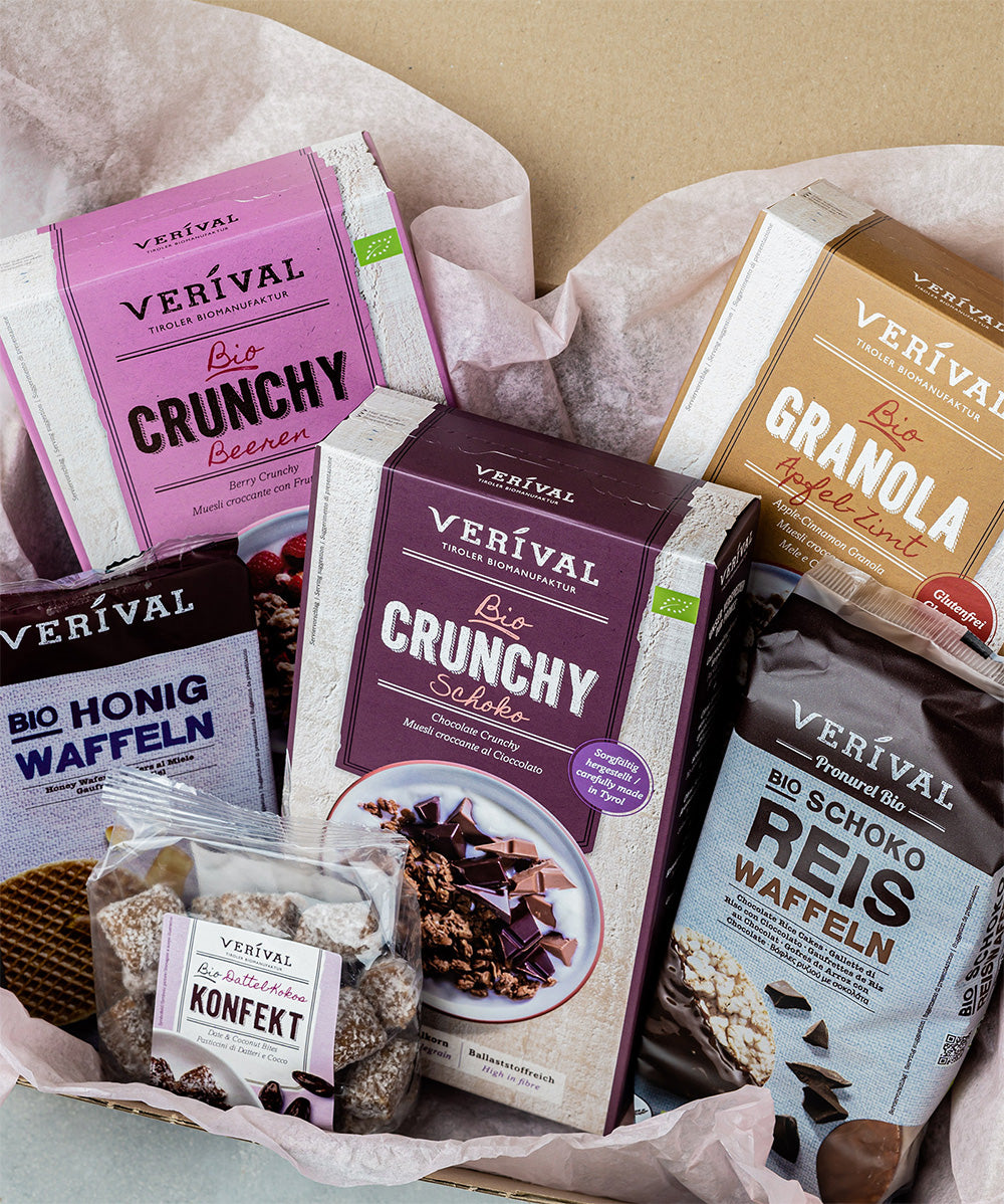 Das Geschenkset „Gute Laune“ von Verival Bio ist wunderschön auf rosa Seidenpapier präsentiert und enthält 100 % Bio Beeren-Granola, Schoko-Granola, Apfel-Zimt Granola, Schoko Reiswaffeln, Honigwaffeln und Dattel-Konfekt – alles von Hand elegant verpackt.