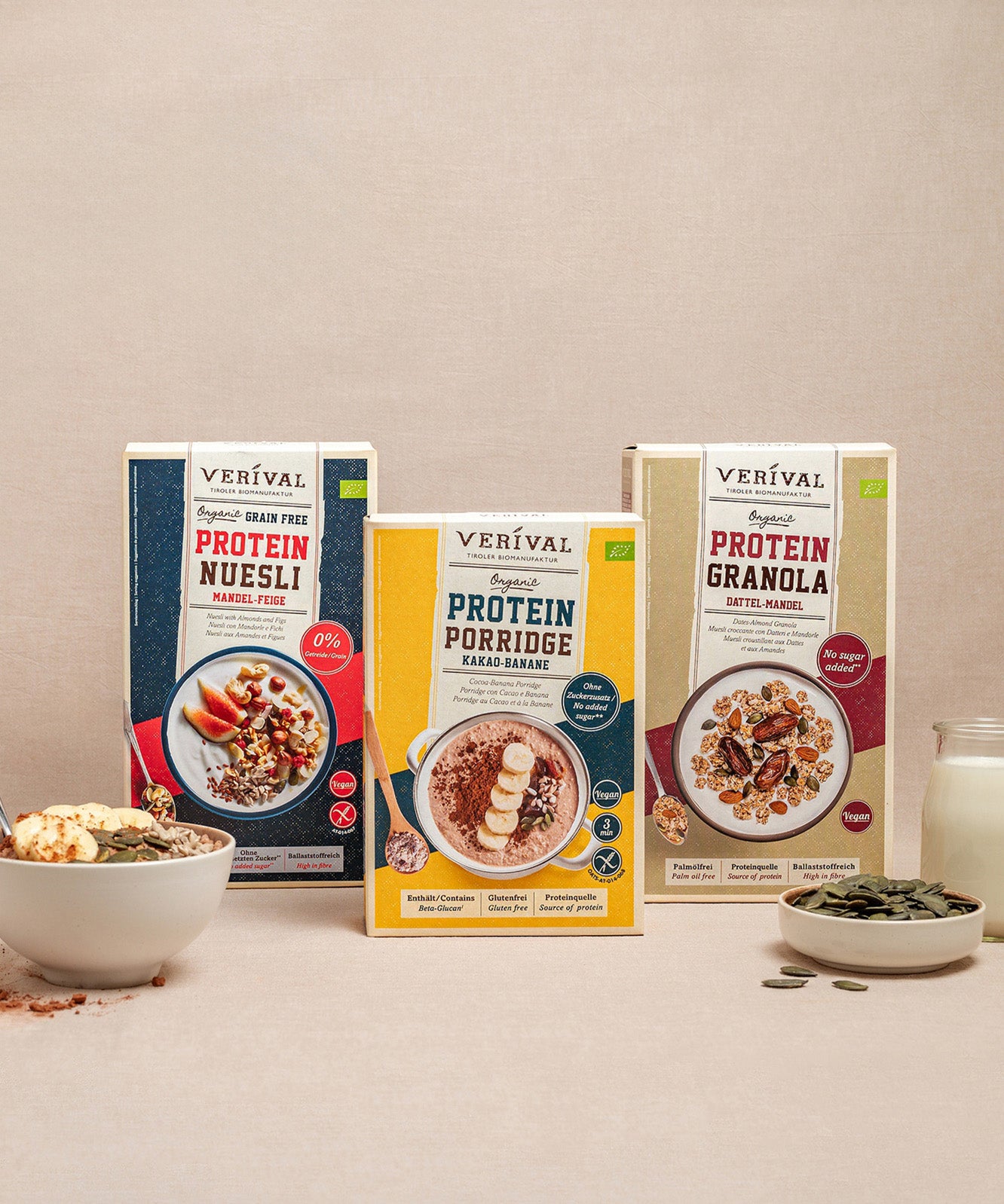 Das Sport Protein-Frühstückspaket von Verival Bio beinhaltet veganes Protein Müsli, Porridge und Granola ohne Zuckerzusatz. Zu sehen vor einer Müslischale mit Milch auf beigem Hintergrund.