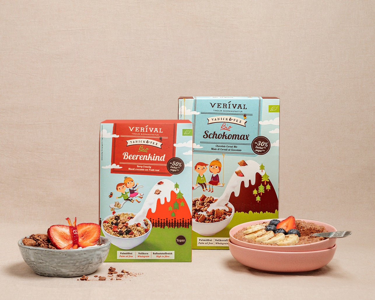 Two packs of Verival muesli stand behind bowls of prepared muesli, garnished with fruit, on a beige background.