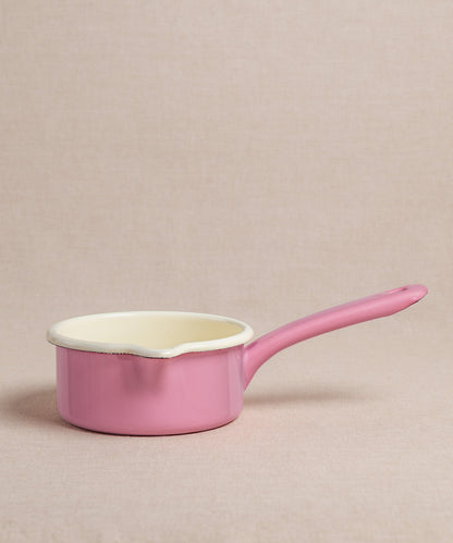 Ein kleiner rosa Emaille-Milchtopf von Riess mit langem Stiel und cremefarbener Innenseite steht auf einer neutralen Oberfläche. Der Topf ist ideal zum Erwärmen von Milch oder zur Zubereitung von Porridge.